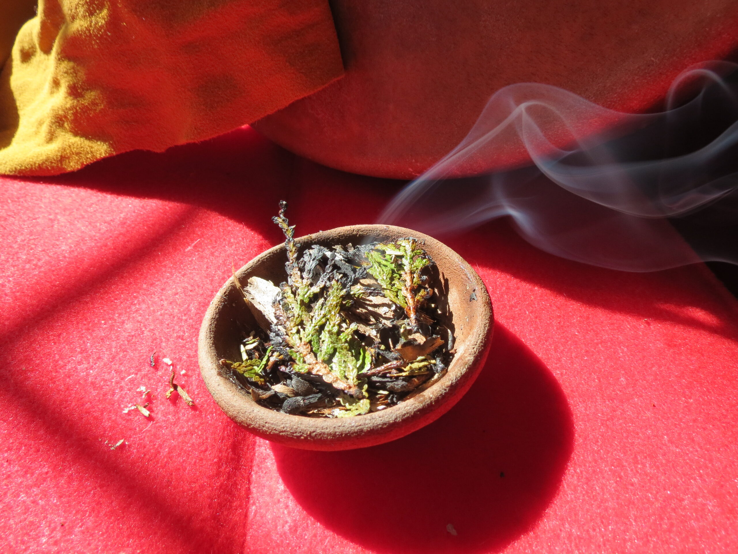 Medicine burning with red fabric and a hand drum in the background.