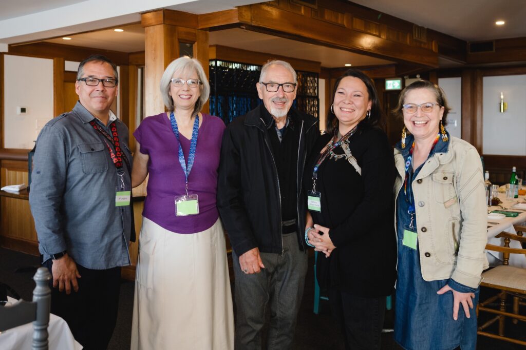 A group of smiling people standing in a dining room.