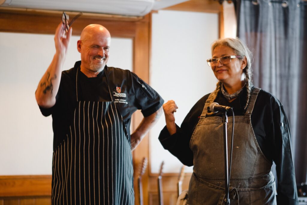 Two chefs, a man and a woman, standing in front of a microphone giving a speech.
